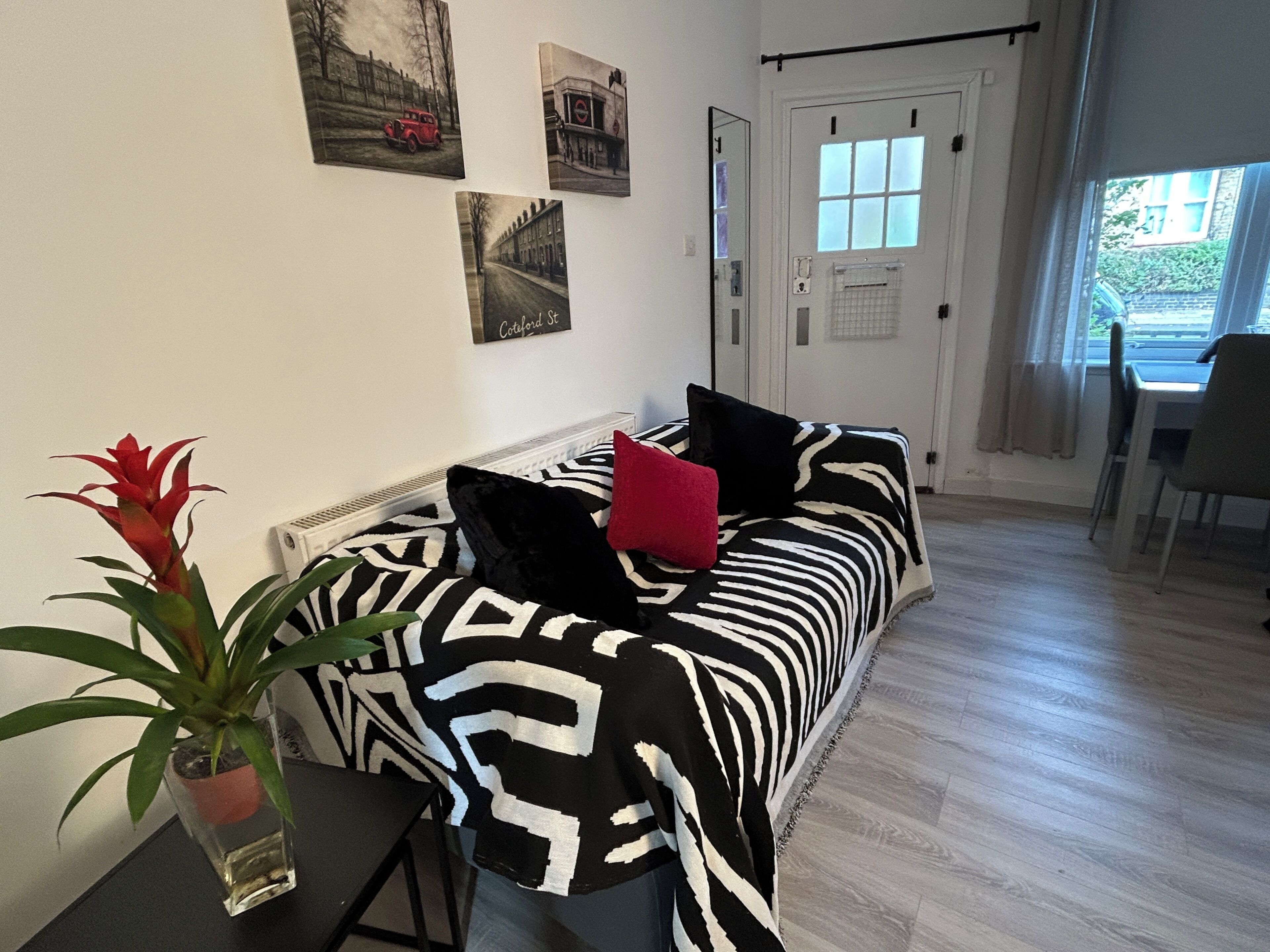 Quarto com sofá, planta em vaso e área de jantar com uma cadeira.