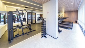 A modern gym with exercise equipment, treadmills, and a mirror wall. - Update by Bhomy (São Paulo)