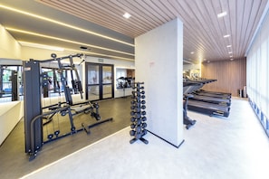 A modern gym with exercise equipment, treadmills, and a mirror wall. - Update by Bhomy (São Paulo)