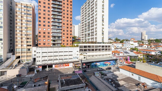 A high-rise building with multiple floors, a parking area, and a mural on the side of a building. - Update by Bhomy (São Paulo)