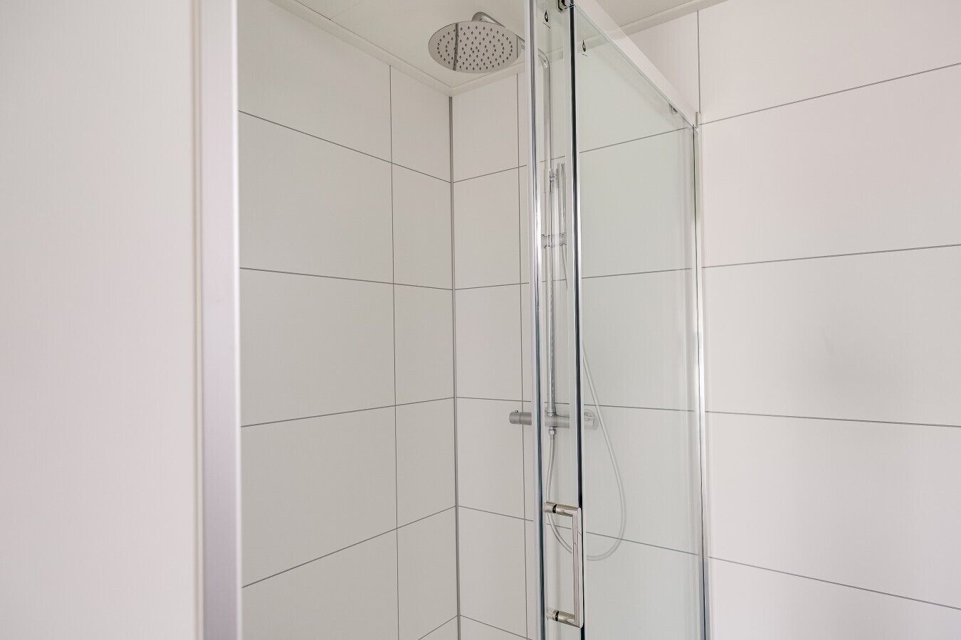 Eine Duschkabine mit Glaswänden, einer Handbrause und einer Bedienkonsole.