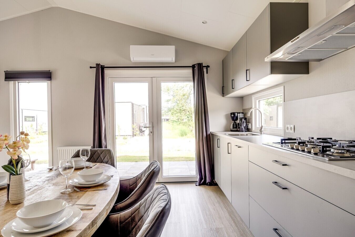 A modern kitchen with a gas stove, a coffee maker, and a dining area with a table set for two.
