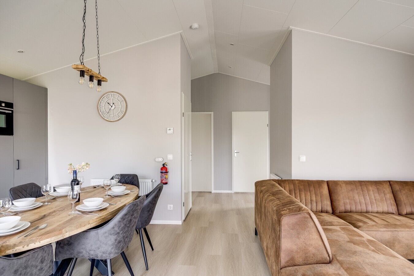 A modern living space with a dining area, a sofa, and a wooden dining table set for four.
