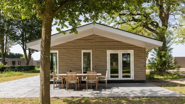 Et moderne hus med terrasse, spisebord og stole.