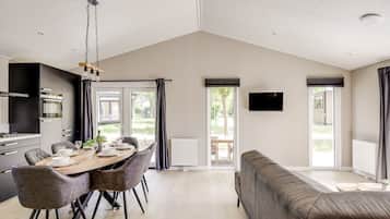 Un intérieur moderne comprenant un coin repas, un canapé et un téléviseur fixé au mur.