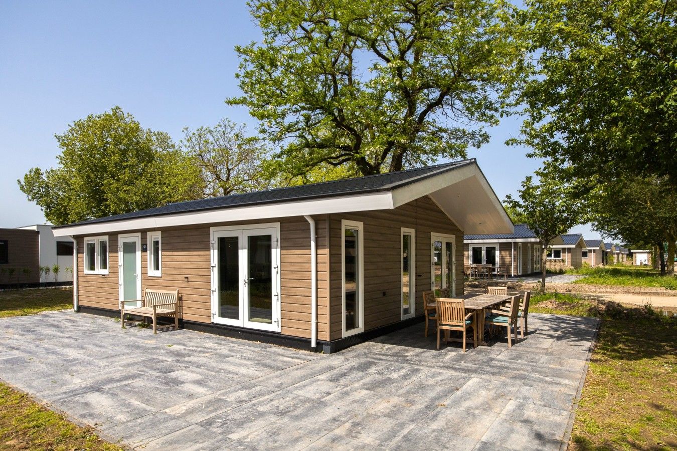 A single-story mobile home with a patio area, a dining table, and chairs.