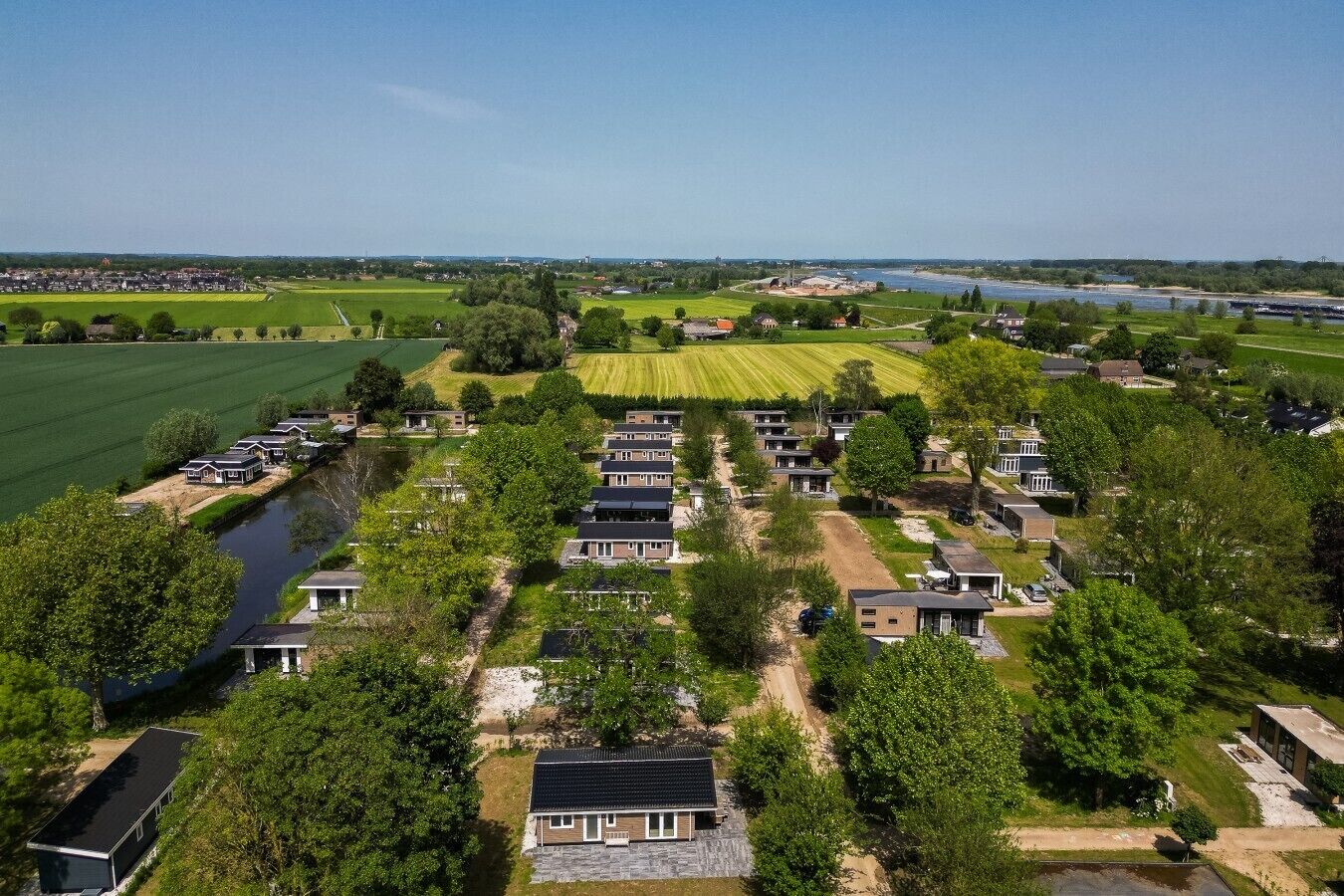 Una zona residencial con casas, un río y campos verdes.