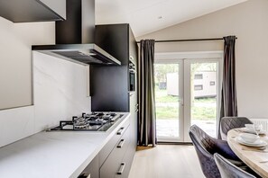 Cocina moderna con estufa a gas, campana extractora y comedor con mesa y sillas.