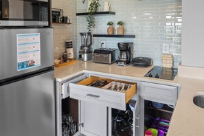 A kitchen with a refrigerator, toaster, coffee maker, and a drawer with utensils. - 2BR apartment with king bed near universal (Orlando)