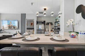 Una cucina moderna con isola centrale, elettrodomestici in acciaio inossidabile e zona pranzo con sedie in pelle nera.
