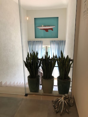 Un interior moderno con un ventanal grande, plantas en macetas y una obra de arte enmarcada en la pared.