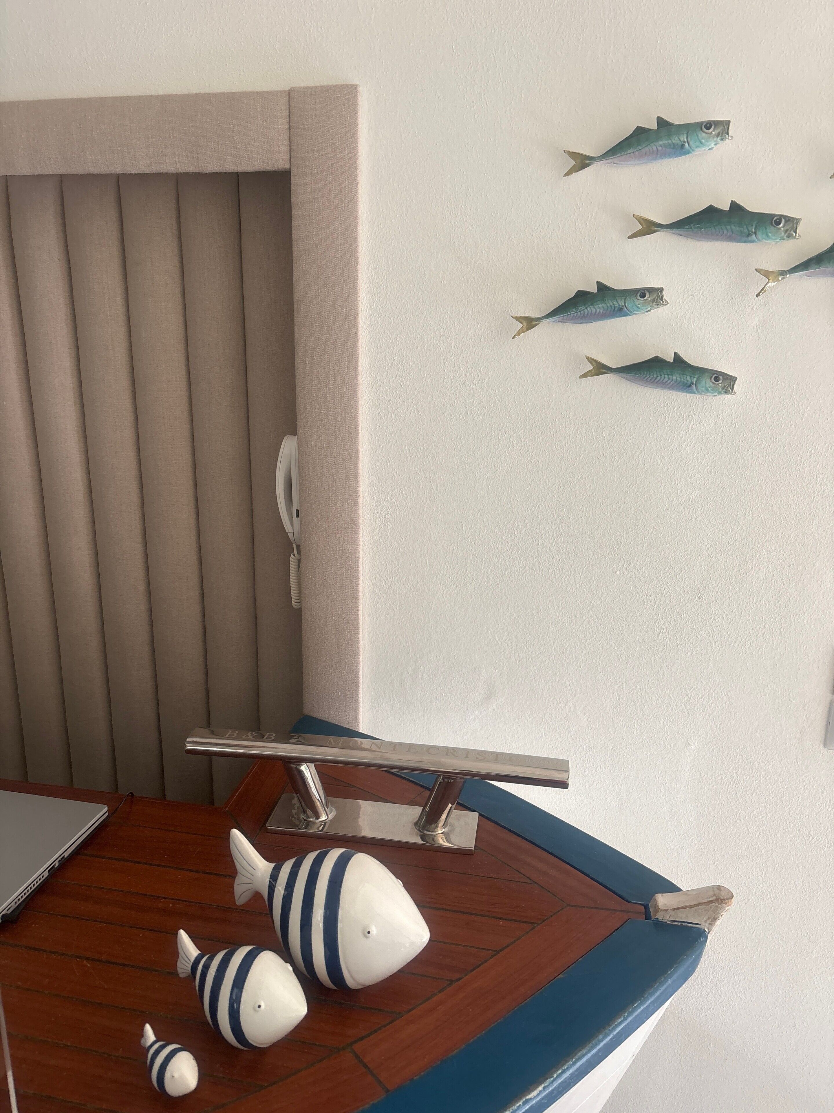 Ein Zimmer mit Holztisch, einem Stuhl, einem Laptop und dekorativen Fischen an der Wand.