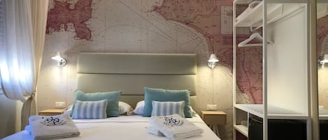 Una habitación de hotel con una cama grande, dos mesitas de noche, un armario y un mapa en la pared.