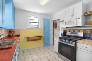 A kitchen with a stove, oven, microwave, and a window.