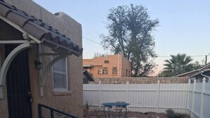 Jacuzzi al pati d'una casa amb un camí de pedra, una tanca de fusta i un edifici amb teulada de rajola.