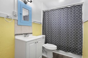 Un bagno con un lavandino bianco, uno specchio blu, un water e una tenda da doccia decorata.