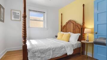 A four-poster bed with a wooden headboard, a bedside table with a lamp, and a window with a view of the desert.