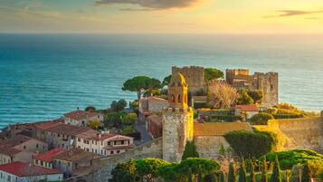 Un pueblo costero con edificios históricos de piedra, un castillo destacado con torre y vistas al mar.