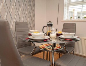 Comedor con mesa lista para dos, que incluye una cafetera, dos tazas y una jarra.