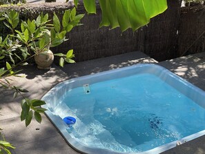 Ein rechteckiger Pool mit blauer Innenauskleidung, umgeben von einem Betonrand und einer dunkel gefärbten Wand.