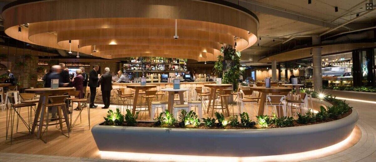 A modern indoor dining area with round tables and chairs, a bar in the background, and a curved seating arrangement.
