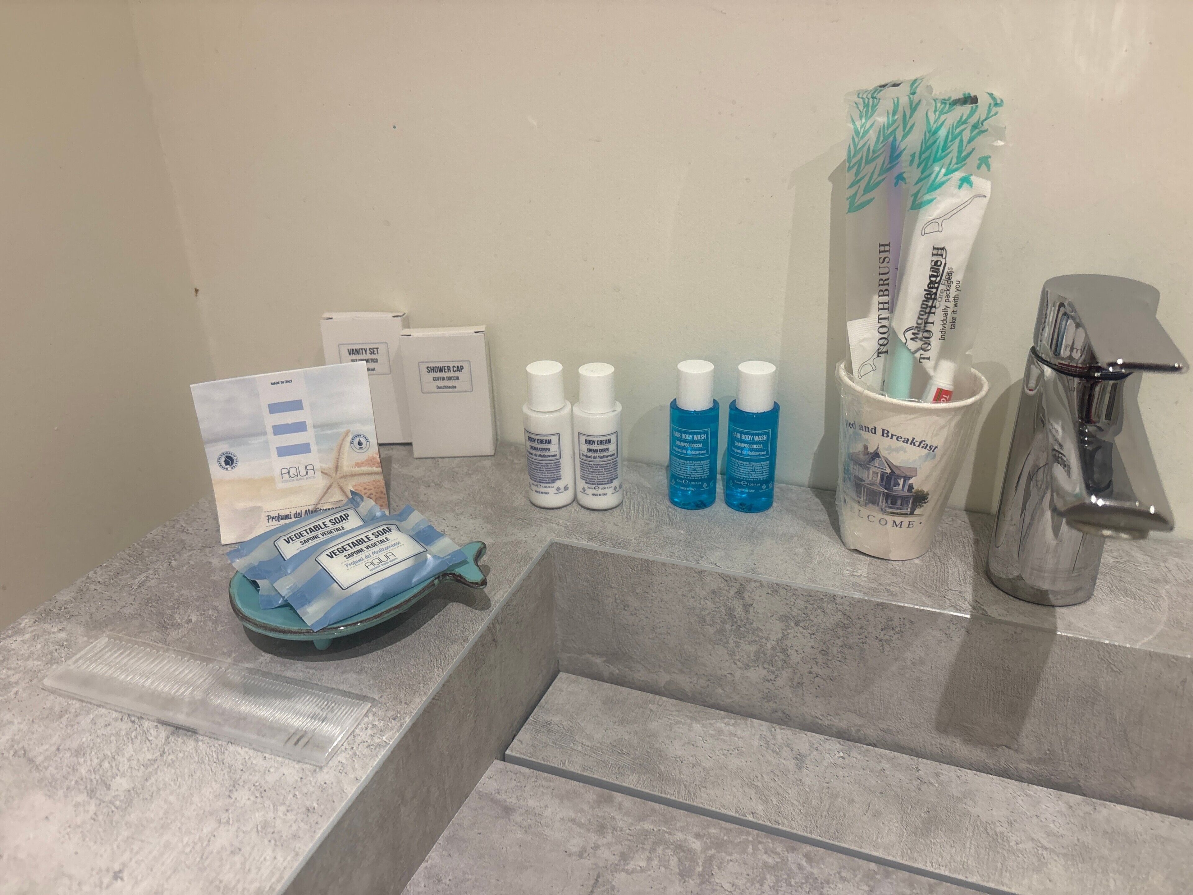A bathroom counter with toiletries including a toothbrush holder, body wash, and a shower cap.