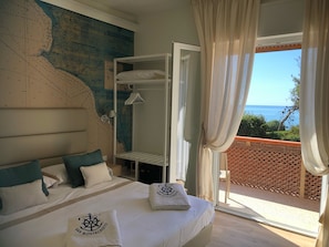 Une chambre d’hôtel avec un lit, une carte accrochée au mur, un balcon avec vue et une serviette ornée d’un logo.