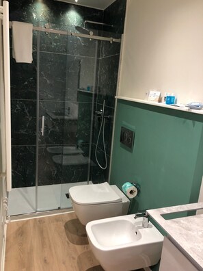 Un baño con ducha de vidrio, inodoro y bidé.
