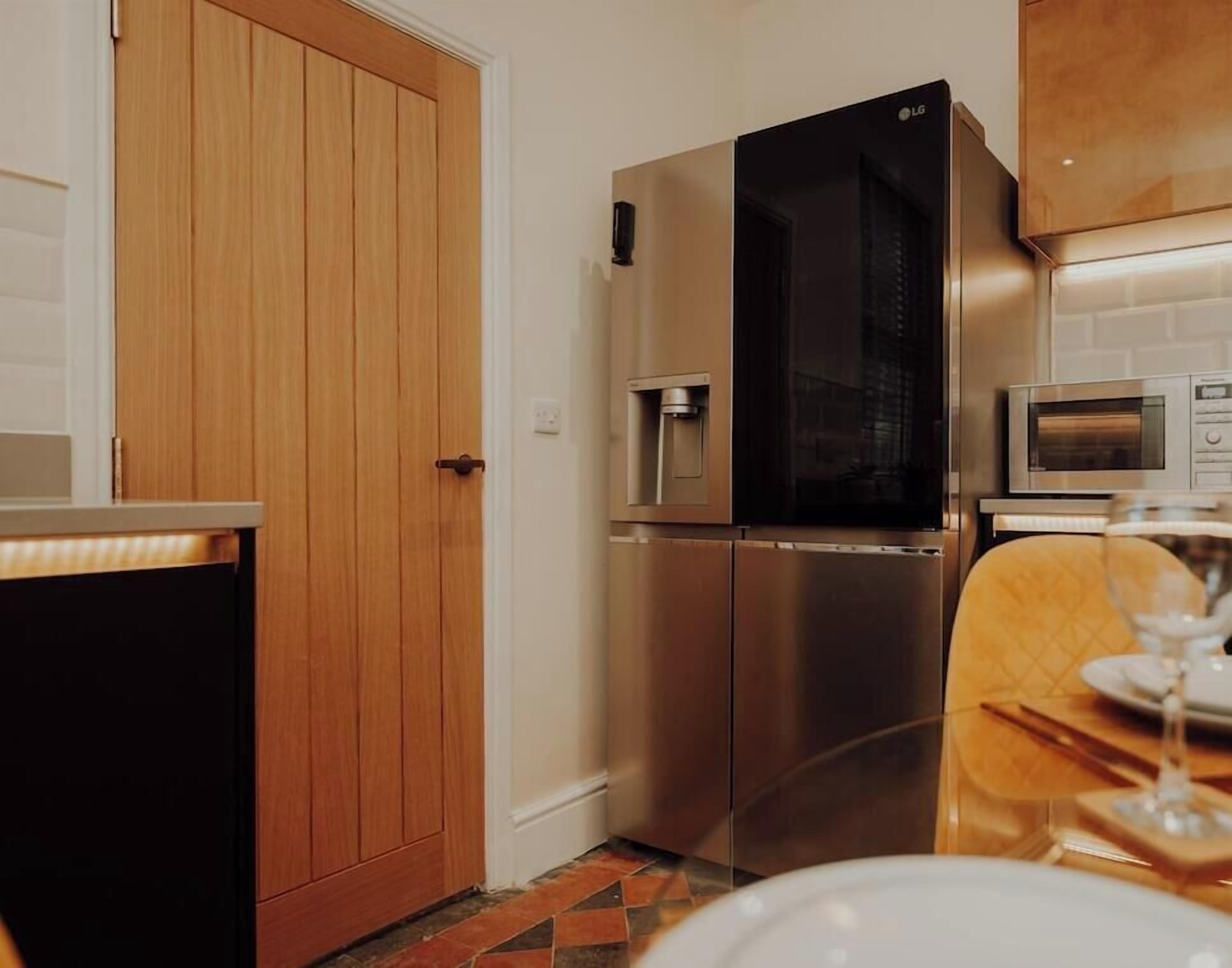 A kitchen with a stainless steel refrigerator, a microwave, and a wooden door.