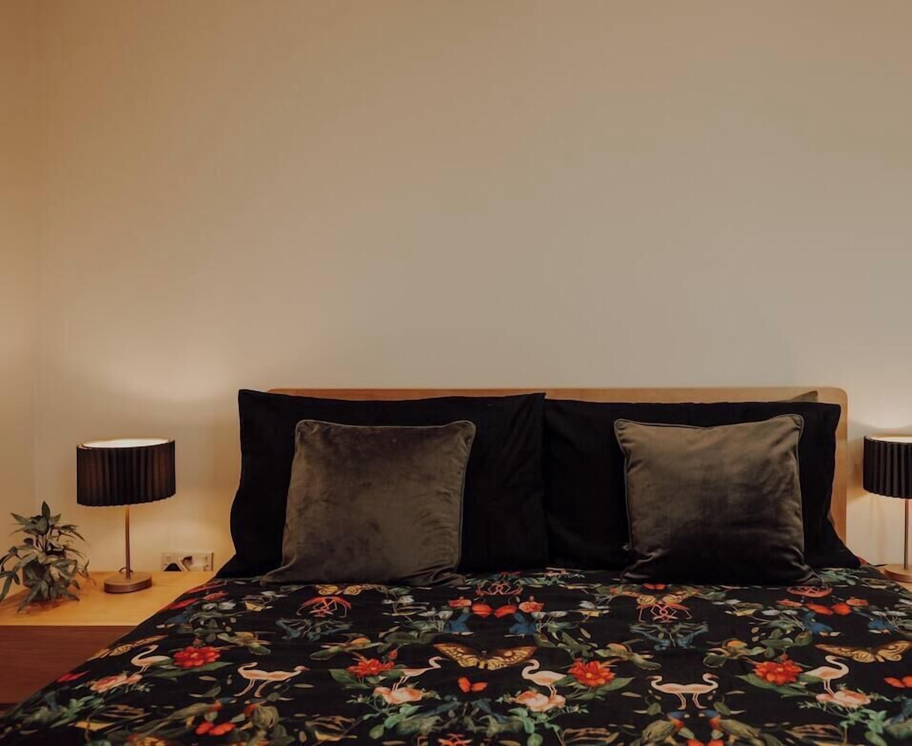 A bed with a floral bedspread, two pillows, and two bedside lamps.