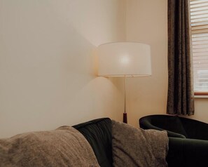 A room with a sofa, a lamp, and a window with curtains.