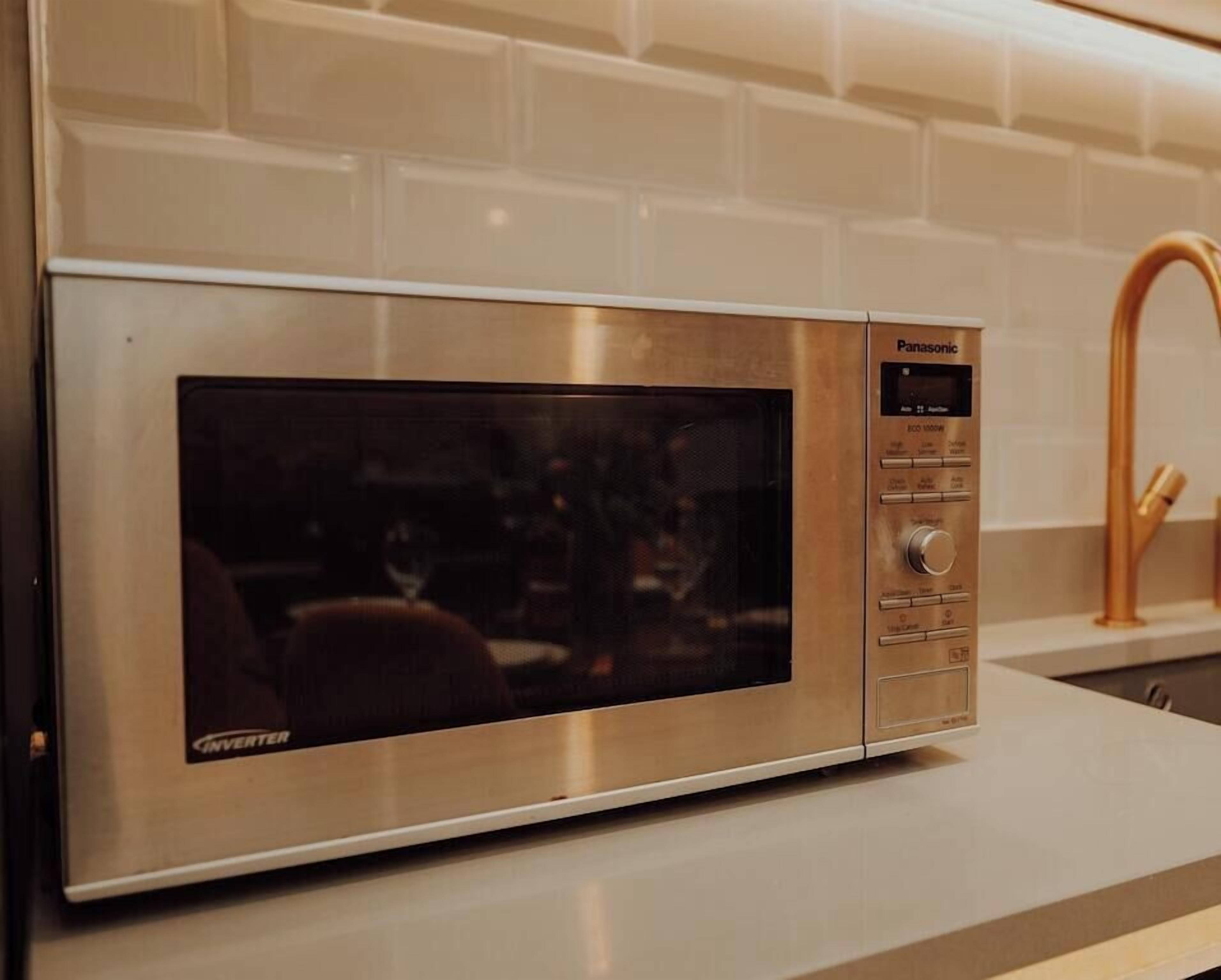 A Panasonic Inverter microwave oven with a digital display and control panel, placed on a kitchen countertop.