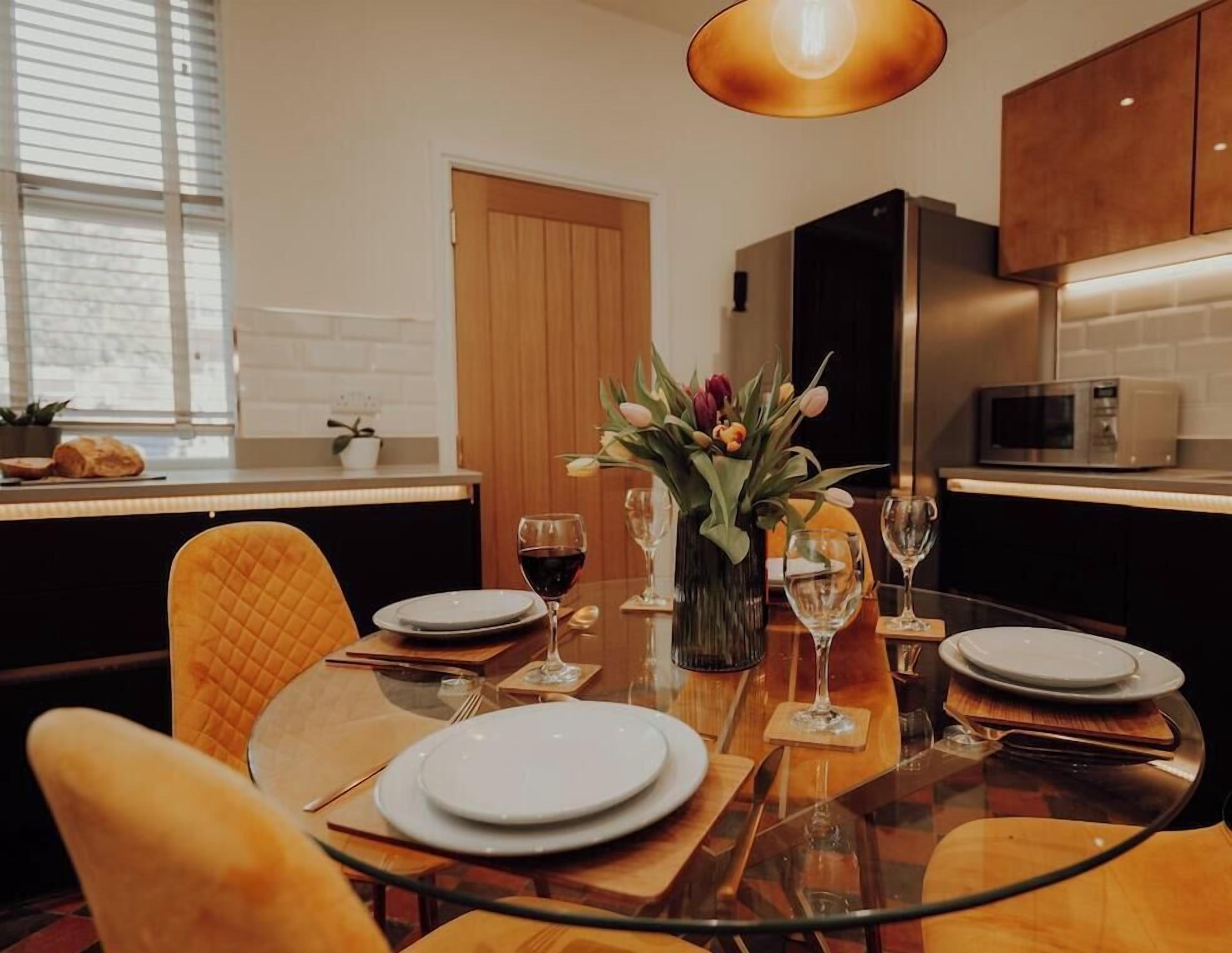 A modern dining area with a glass table, wooden chairs, and a vase with flowers.