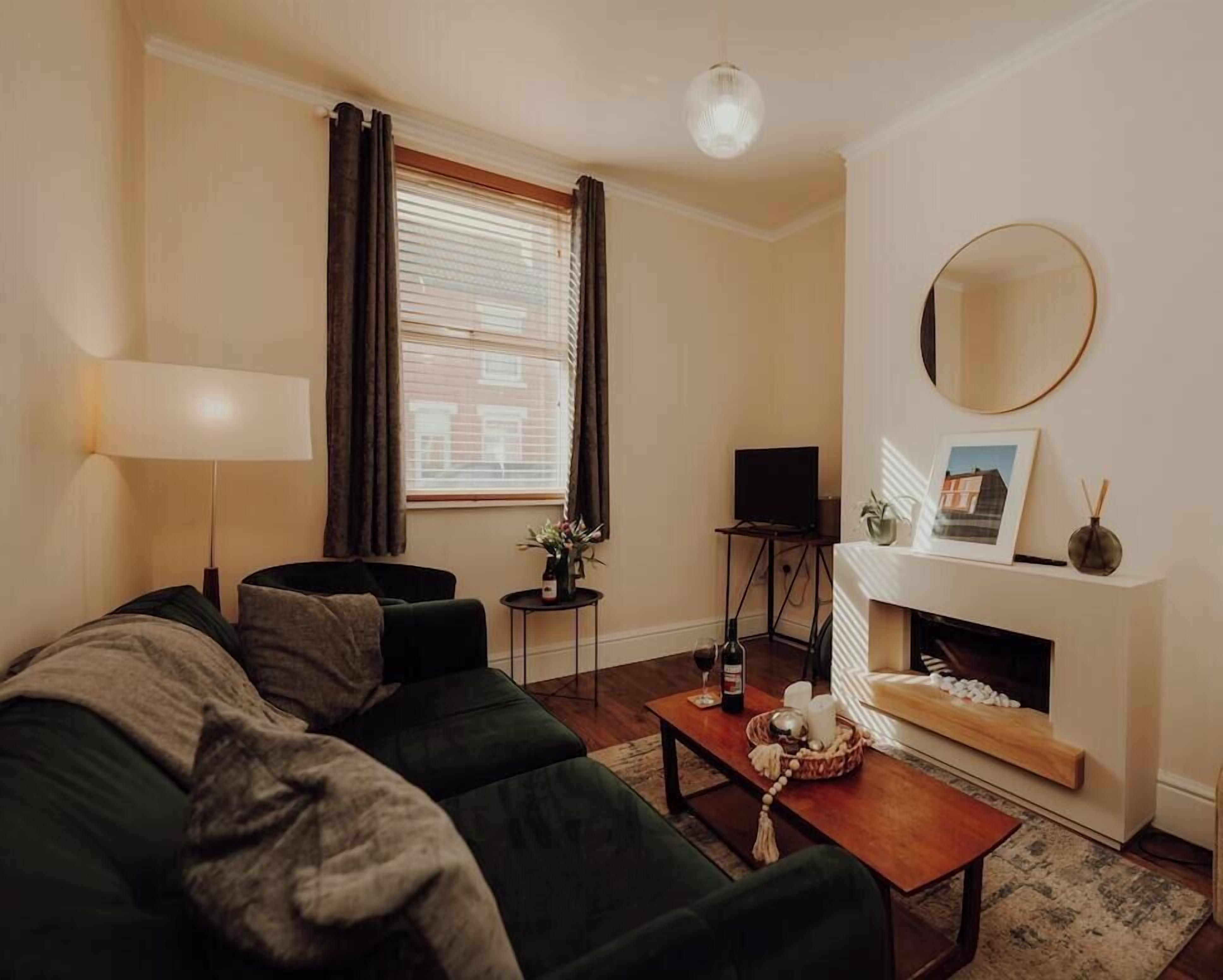 Un salon comprenant un canapé, une table basse, une cheminée, un téléviseur et une lampe.