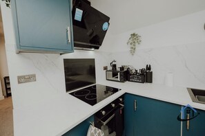 Eine moderne Küche mit eingebautem Herd, Mikrowelle und Kaffeemaschine auf der Arbeitsfläche.