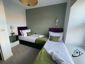 Ein Hotelzimmer mit zwei Betten, einem Nachttisch mit Lampe und einer kleinen Pflanze.