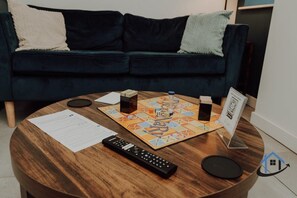 A round wooden table with a board game, a remote control, and papers. - Apt 2 Manor House - 2 Bed 1 bath sleeps 5 parking (Desborough)