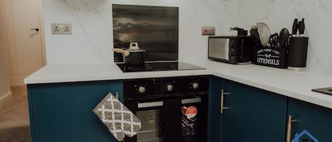 Una cocina con estufa, horno, microondas y un portalápices.