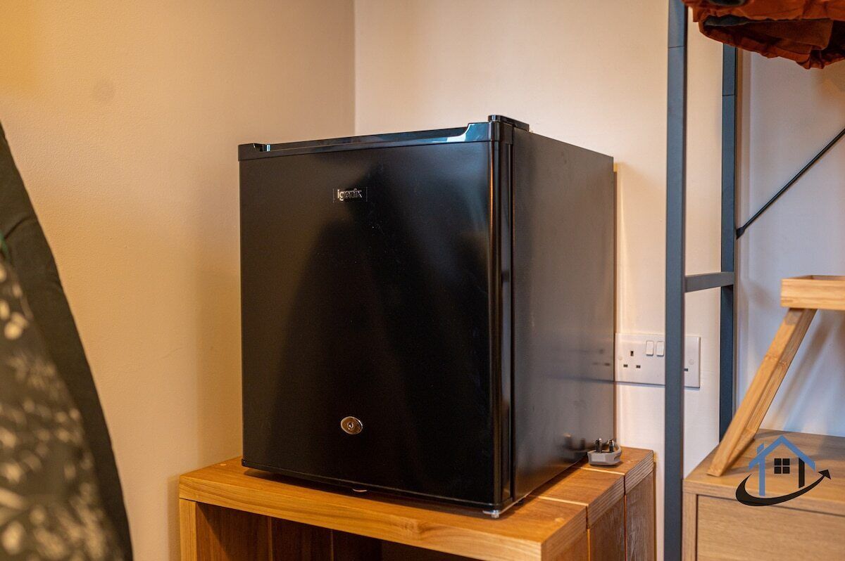 A black refrigerator on a wooden cabinet.