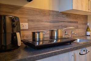 Een keuken met een inbouwfornuis, een koffiezetapparaat en een wijnfles.