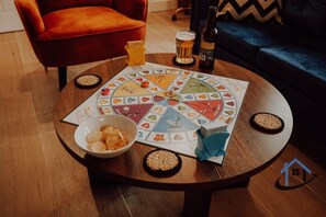 Ein Brettspiel auf einem runden Tisch mit Snacks, einer Schüssel und einer Bierflasche.