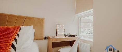 Un dormitorio con una cama, un escritorio con silla, una ventana con persianas y un radiador.