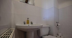 A bathroom with a white sink, toilet, and a vent. - The Plough, 4 beds, sleeps 9, free parking (Caldecott)