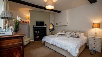 A bedroom with a bed, bedside tables, a dresser, a television, and a lamp.