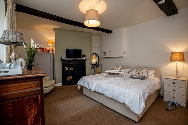 A bedroom with a bed, bedside tables, a dresser, a television, and a lamp.