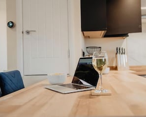 A laptop on a wooden table with a glass of white wine and a bowl of food. - Shambles Retreat, studio, parkingx2 (Wiltshire)