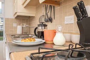 A kitchen counter with a plate of food, a coffee maker, a milk jug, and a knife block. - Ironside House 3 bed house, sleeps 8 parking (Thrapston)