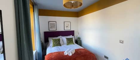 Una habitación de hotel con una cama, una mesita de noche, una lámpara y una pared con un logotipo.