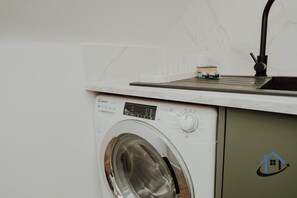 Eine kompakte Waschmaschine und Trockner-Kombination mit Bedienfeld und schwarzem Schlauch.