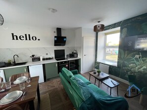 A compact living space with a kitchenette, a dining area, and a sofa. - Apt 4 Manor House - 1 Bed 1 bath sleeps 2 parking (Desborough)